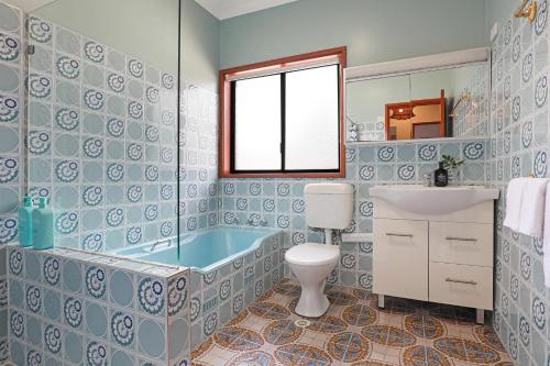 a bathroom with a tub and a toilet and a sink at Thirroul Beach Apartments in Thirroul