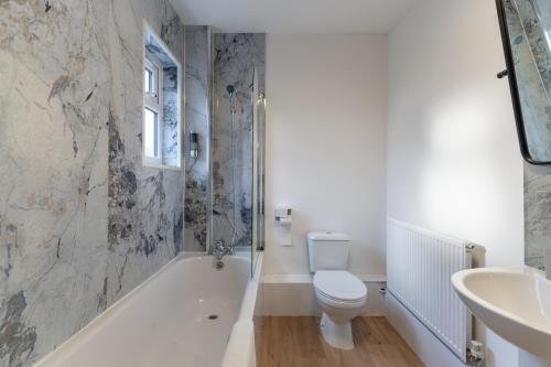 a bathroom with a toilet and a tub and a sink at TI Derby Escape - Free Wifi, Free Parking in Derby
