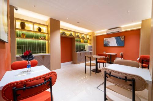 a restaurant with orange walls and tables and chairs at Vibe Hotel Managed By Nicecy in Ho Chi Minh City