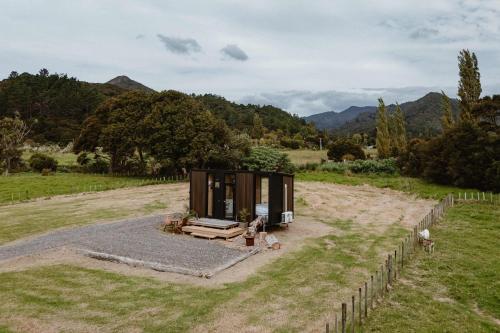 a tiny house in a field with a fence at Omoho Stream X by Tiny Away in Kennedys Bay