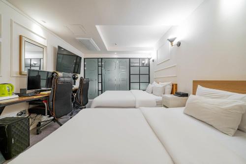 a bedroom with two beds and a desk with a computer at Hotel Avenue in Tansa-gol