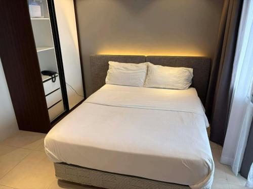 a bed with white sheets and pillows in a room at Top Floor Studio Non-Resort Unit Tambuli Tower D in Maribago