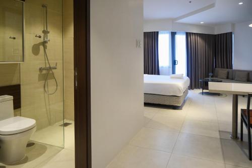 a hotel room with a bed and a bathroom at Top Floor Studio Non-Resort Unit Tambuli Tower D in Maribago