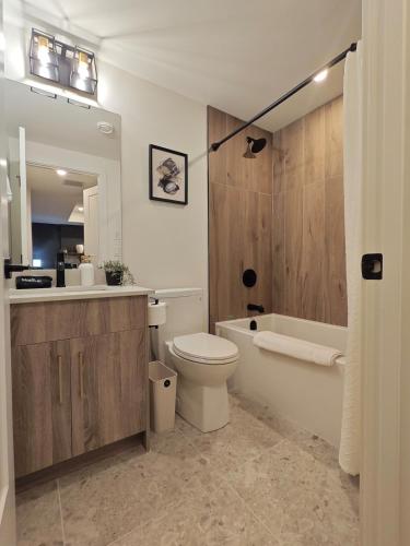 a bathroom with a toilet and a tub and a sink at New Luxury MountainView Downtown2B2B RooftopHottub in Canmore