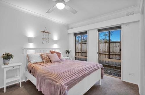 a white bedroom with a bed and two windows at Large Pet Friendly Island Escape in Newhaven