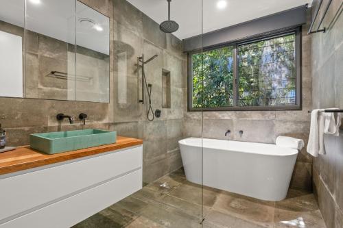 a bathroom with a tub and a sink and a window at Grottamare in Lennox Head