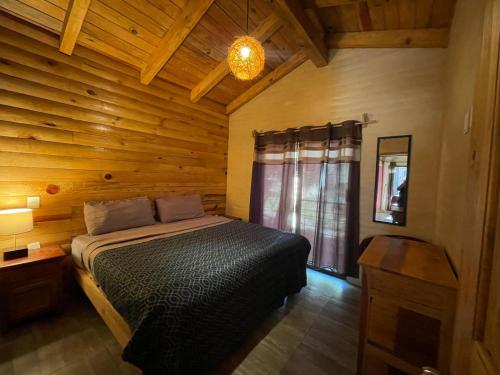 a bedroom with a bed in a wooden room at Cabañas Quinta de Cuevas in Mazamitla