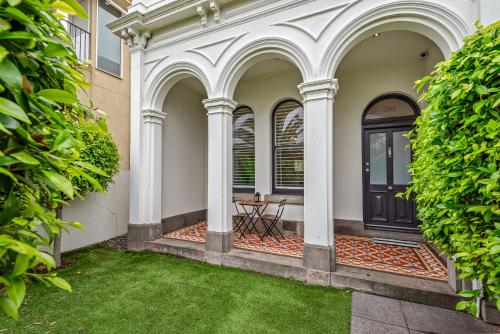 a front porch with a black door and green grass at Complete Host Middle Park House in Melbourne