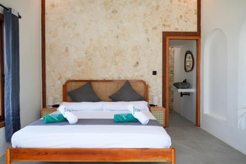 a bedroom with a bed with white sheets and green pillows at Ombara Resort Mentawai in Katiet