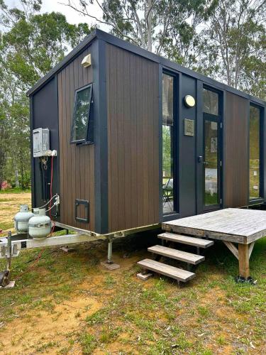 a tiny house with a bench and a table at Mirror Reflections 2 by Tiny Away in Tamborine