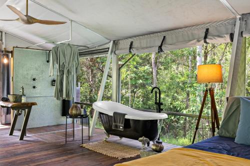a bedroom with a tub and a bed and a window at Starry Nights Luxury Camping in Woombye