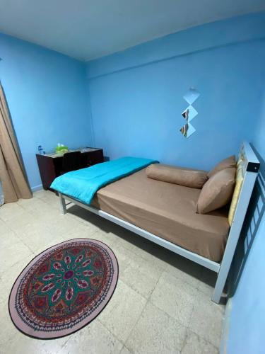 a bedroom with a bed with a blue wall at Wel home stay in Pulau Gilimota