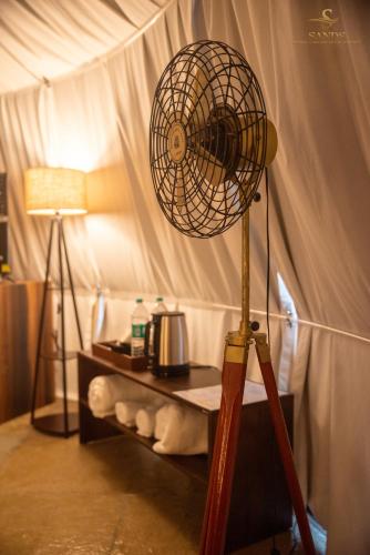 a room with a fan and a table with a lamp at Sands - Tajpur in Tajpur