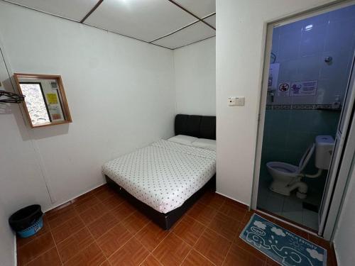 a small room with a small bed and a toilet at ACF Guest House in Sungai Lembing