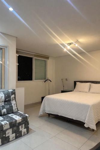 a bedroom with a bed and a chair at Flat Lounge 22 Setor Oeste in Goiânia