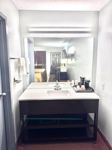 a bathroom with a sink in front of a mirror at Owensville Inn in Owensville