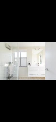 a white bathroom with a sink and a mirror at Retreat to Pisa in Mount Pisa