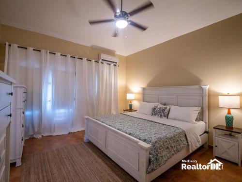 a bedroom with a white bed and a ceiling fan at Casa Estrella, Relaxation Begins in Sosúa