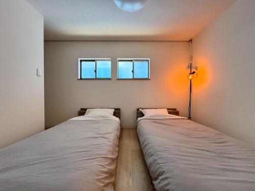two beds in a room with a window at ura BETTEi 別邸 in Okayama