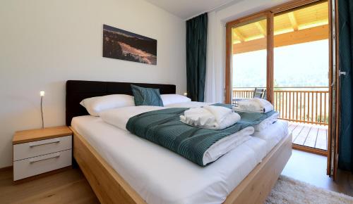 a bedroom with a large bed with a balcony at Premium Apartments am Weißensee in Weissensee