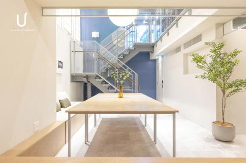 a table in the middle of a room with stairs at unito hotel residence Kyoto Station North in Kyoto