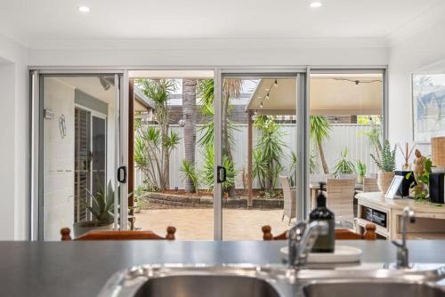 a kitchen with a view of a patio with palm trees at Pet Friendly Beachside Hideaway - Lazy on Lowry in Woorim