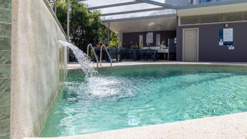 a pool with a water fountain in a building at Waterline Direct Poolside Apartment in Agnes Water