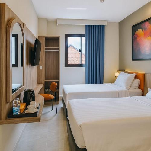 a hotel room with two beds and a tv at Front One Hotel Mesir Surabaya in Surabaya