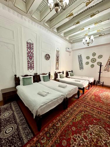 two beds in a room with a red rug at Hotel Ravshan Boutique in Bukhara