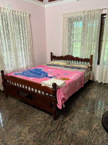 a bedroom with a bed with a pink blanket at VallabhanAnnexHomestay in Varkala