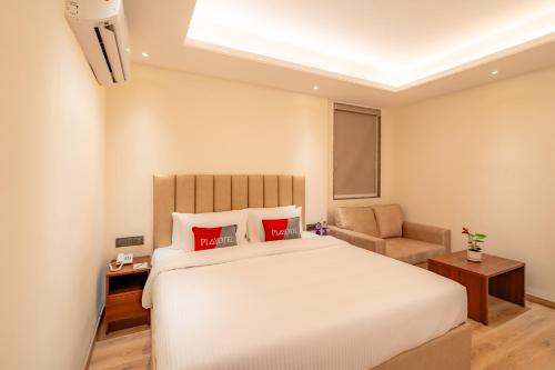 a bedroom with a large white bed and a chair at Playsales SSR in Indore
