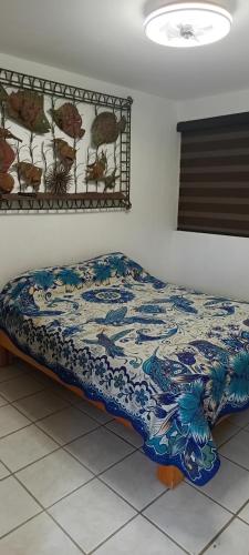 a bed in a room with a blue and white blanket at descanso ideal con alberca in Cihuatlan