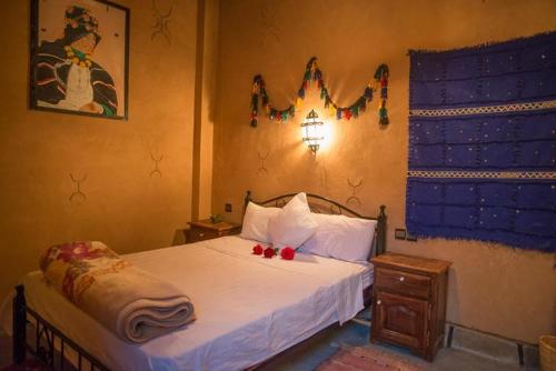 Un dormitorio con una cama con dos rosas rojas. en Maison D' hôtes Ait Hmid, en Nkob