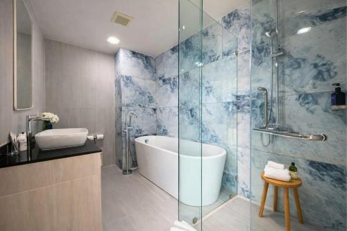 a bathroom with a tub and a glass shower at Aqua Maya Phuket in Patong Beach