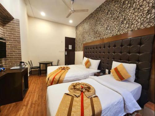 a hotel room with two beds and a television at Hotel Raunak in Kolkata
