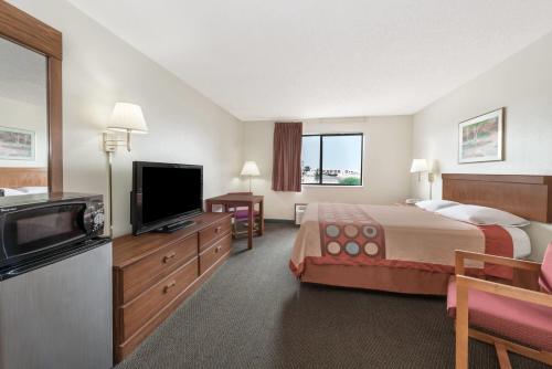 a hotel room with a bed and a flat screen tv at Super 8 by Wyndham Smithville Kansas City in Smithville