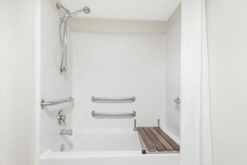 a bathroom with a bath tub with a wooden seat at Super 8 by Wyndham Smithville Kansas City in Smithville