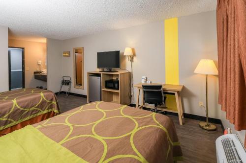 a hotel room with two beds and a desk with a television at Super 8 by Wyndham Smithville Kansas City in Smithville