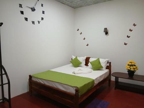 a bedroom with a bed with green pillows and a clock at Canal Resort Udawalawa in Ratkarawwa