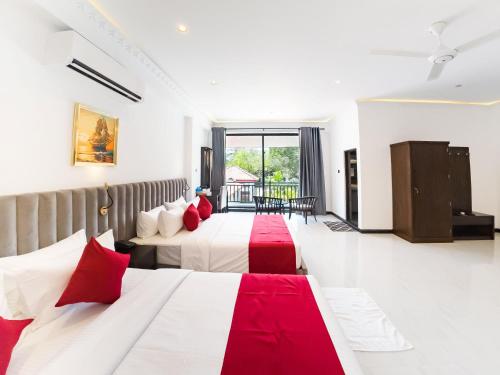 two beds in a hotel room with red pillows at The Grand Moon River Hotel in Kataragama