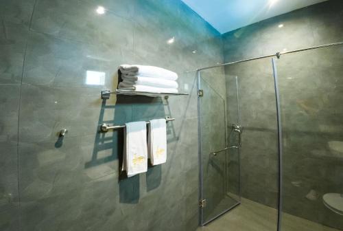 a bathroom with a shower and some towels at The Grand Moon River Hotel in Kataragama