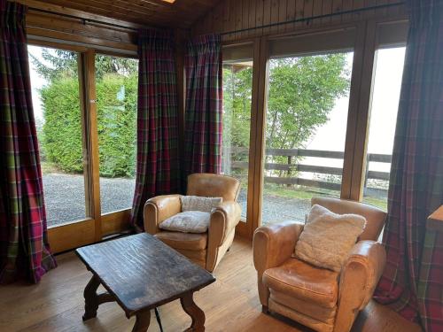 a living room with two chairs and a table and windows at Pet-friendly chalet in Veysonnaz in Veysonnaz