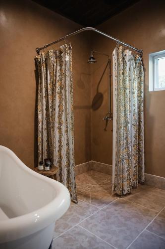 a bathroom with a shower and a toilet and a tub at Blacksmith House on Main in Tocumwal