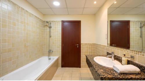 a bathroom with a tub and a sink at Devine Holidays JBR in Dubai