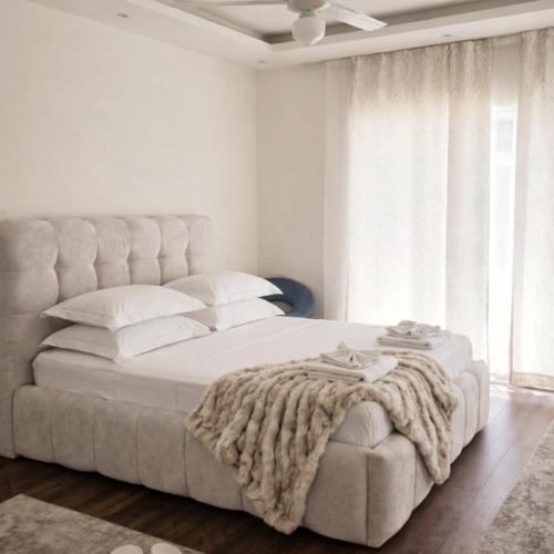 a white bedroom with a large bed with a blanket on it at Villa Aqua Vista in Mostar