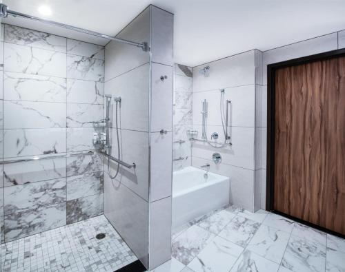a bathroom with a tub and a shower with a glass door at The Charter Hotel Seattle, Curio Collection By Hilton in Seattle