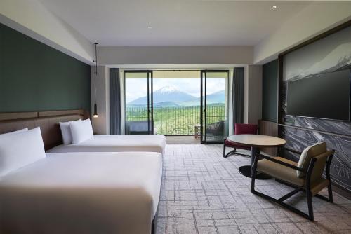 a hotel room with two beds and a table and a tv at Fuji Speedway Hotel, in The Unbound Collection by Hyatt in Oyama