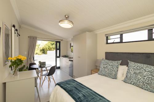 a bedroom with a bed and a kitchen with a table at Catalyst Guest House in Cape Town