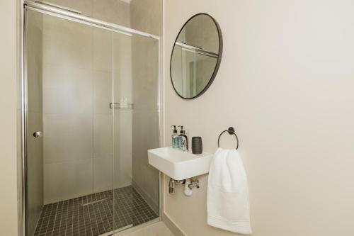 a bathroom with a shower and a sink and a mirror at Catalyst Guest House in Cape Town