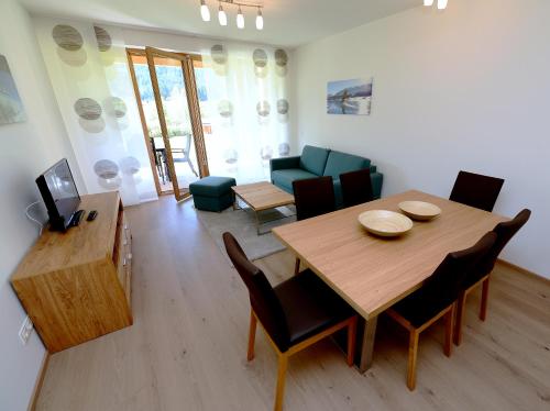 a living room with a wooden table and a dining room at Premium Apartments am Weißensee in Weissensee